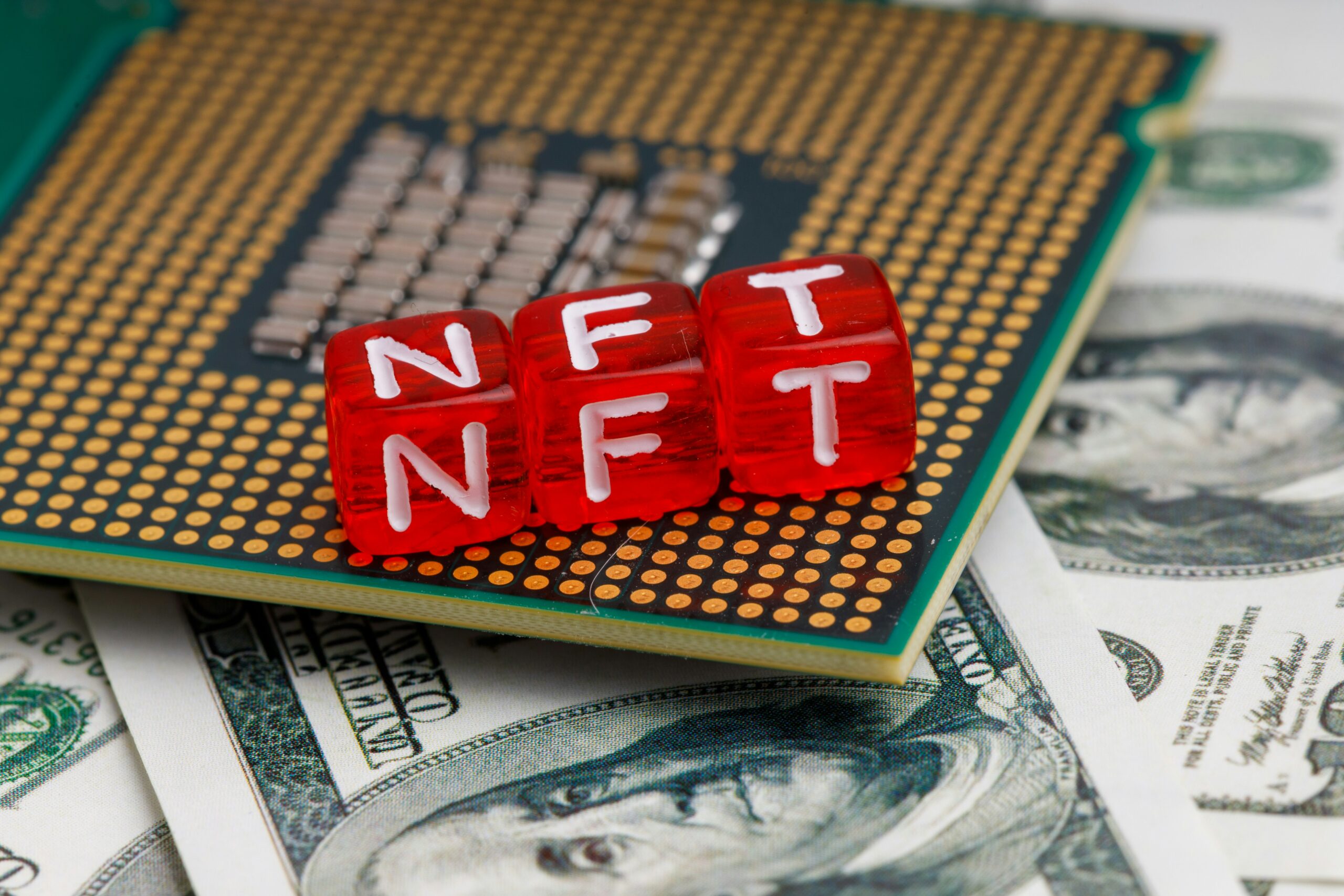red letter blocks spelling NFT on top of dollar bills